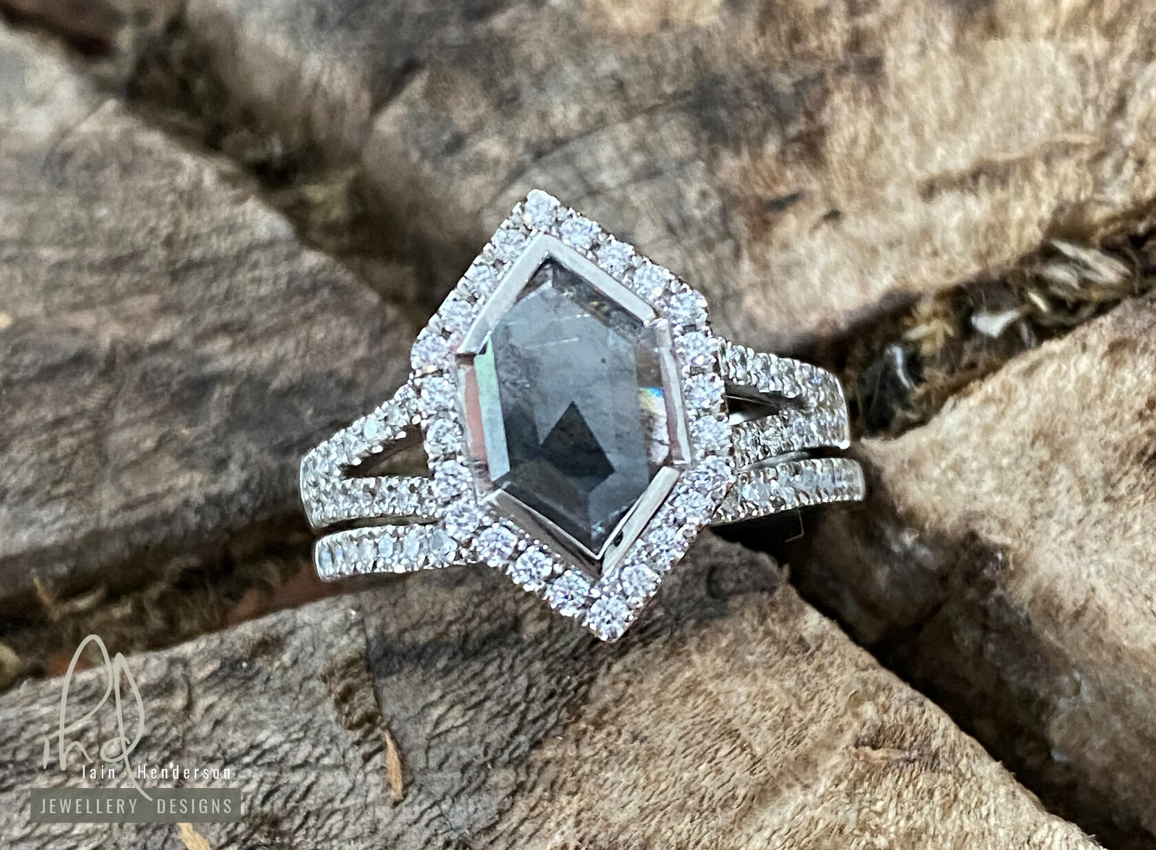 Halo style engagement ring with a salt and pepper marquise shaped diamond, a split shank and a matching wedding ring
