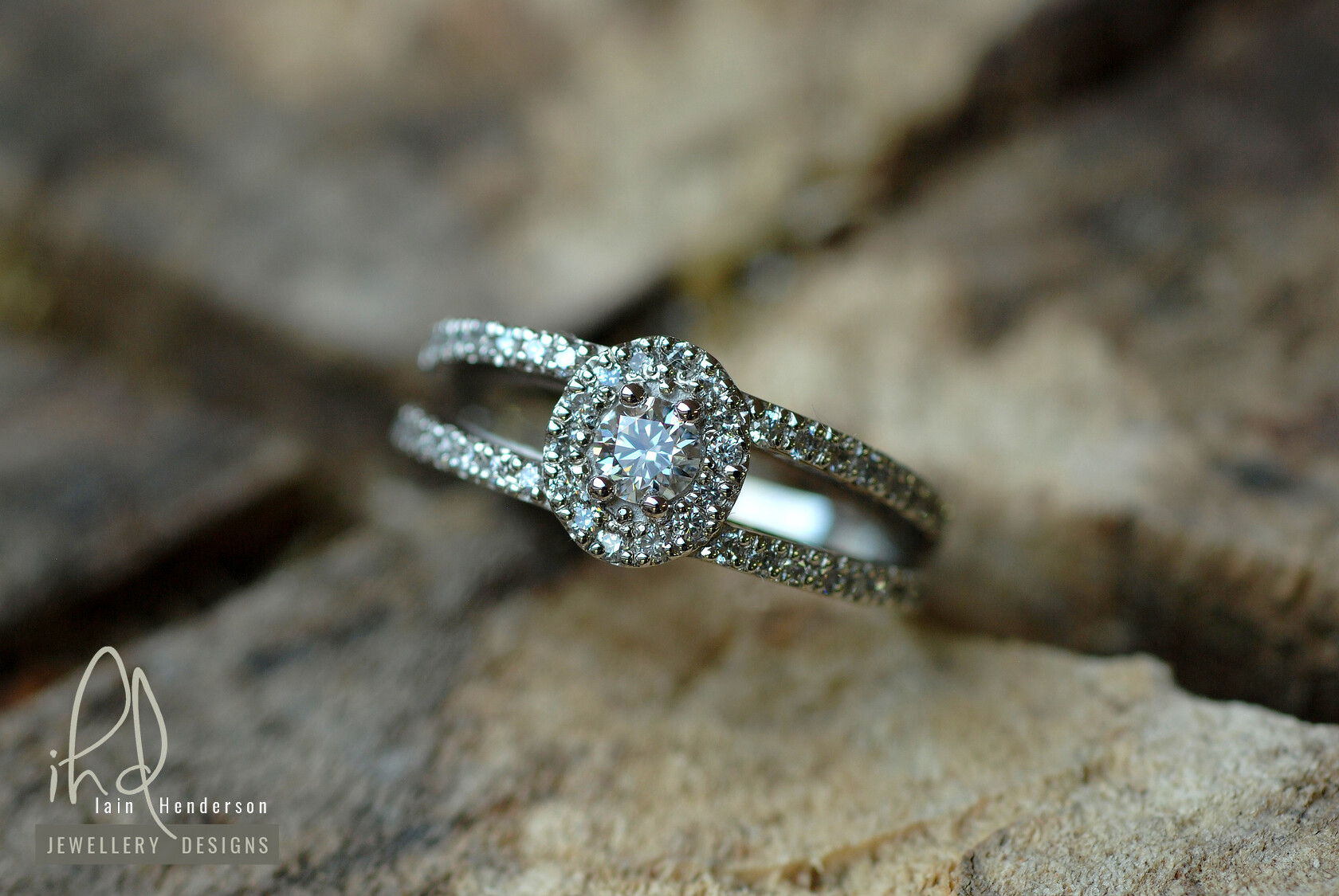 Halo shaped platinum engagement ring with a split shank and diamonds on the shoulders