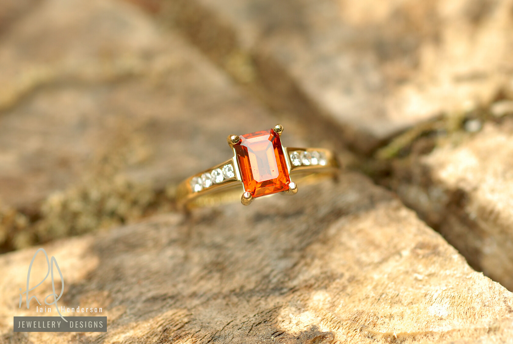 0018ct yellow gold engagement ring with an orange sapphire and channel set round diamonds on the shoulders