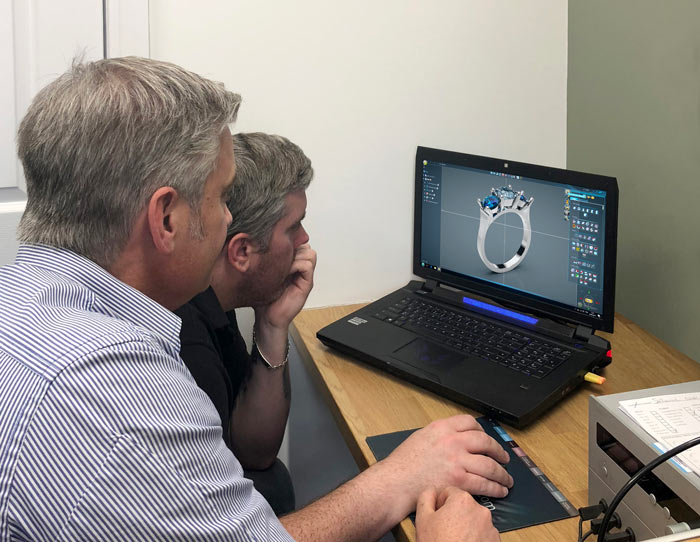 Two men in front of a laptop computer, 3D remodelling a new ring design